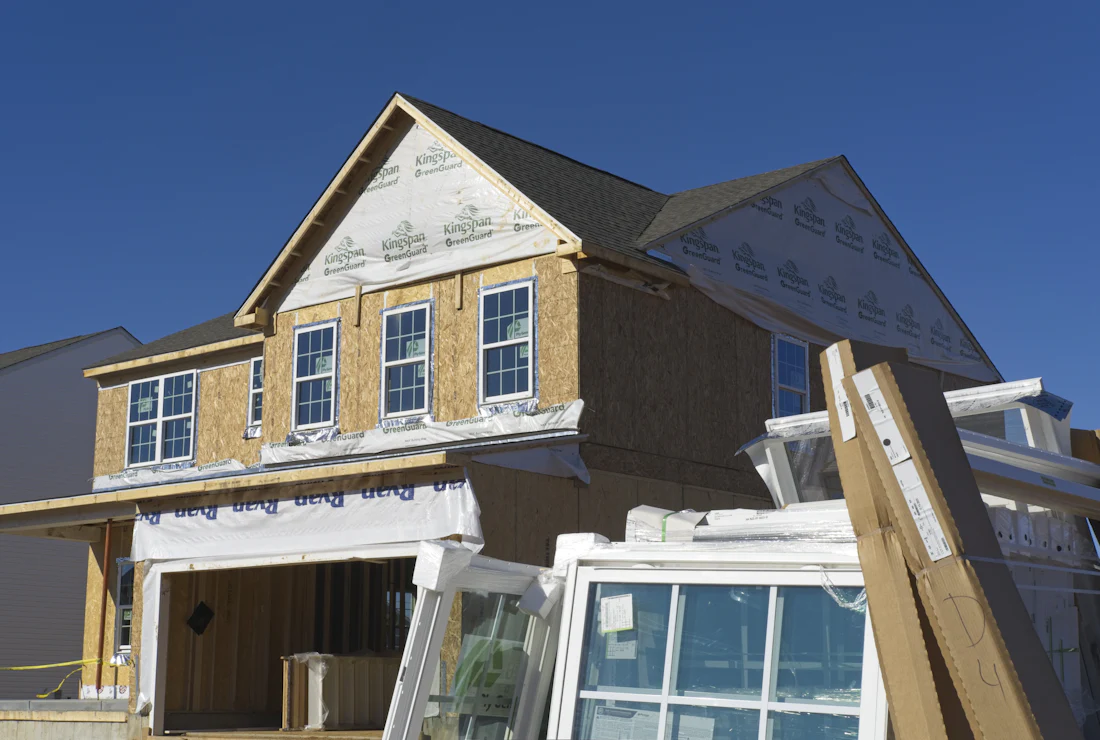 A wood-frame house under construction under a blue sky